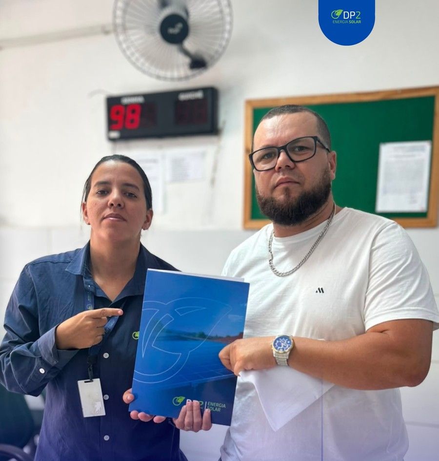 Bruno segura a pasta do projeto ao lado da consultora da DP2, que aponta para o documento