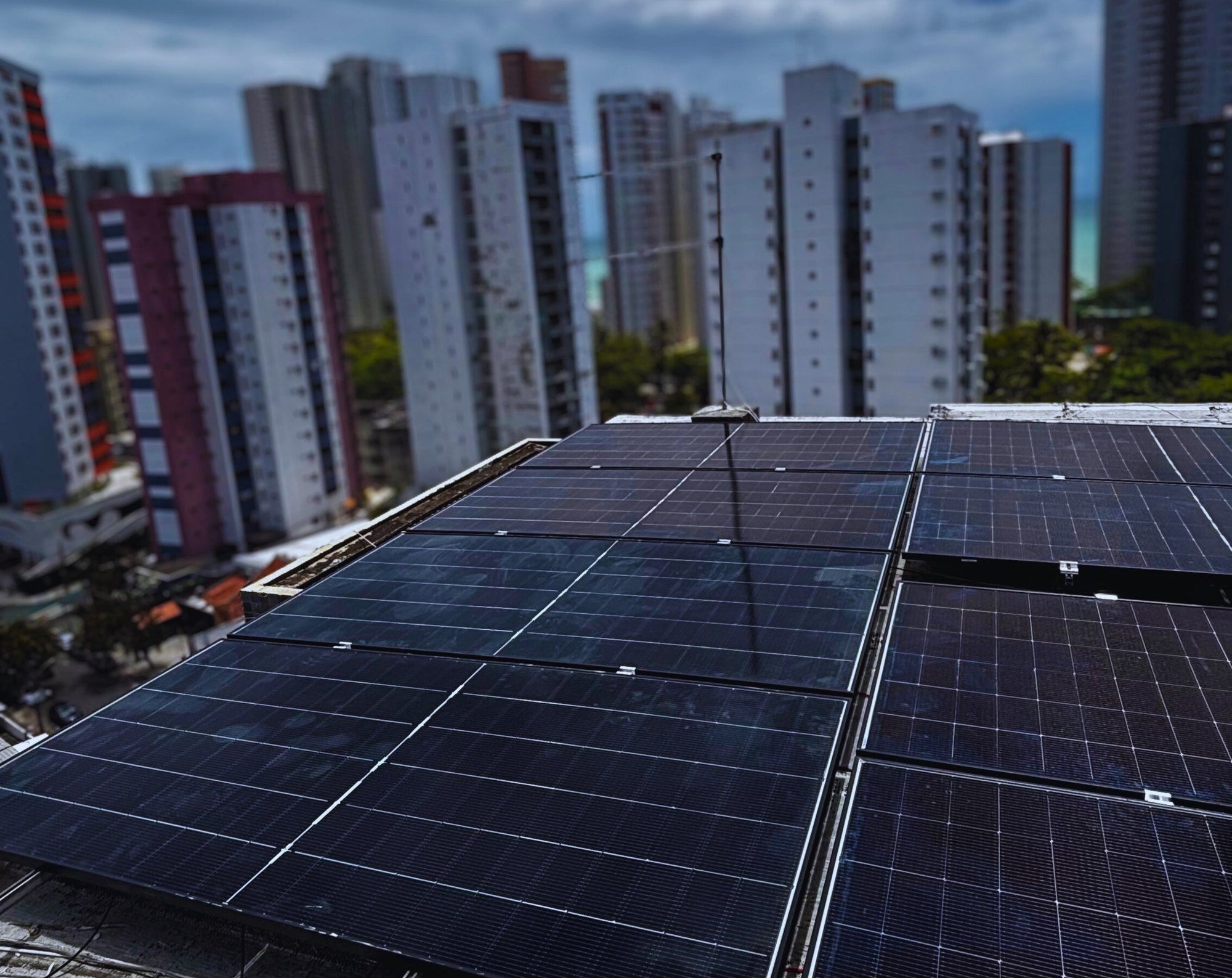 Módulos solares na laje de um prédio em Boa Viagem, com edifícios ao fundo
